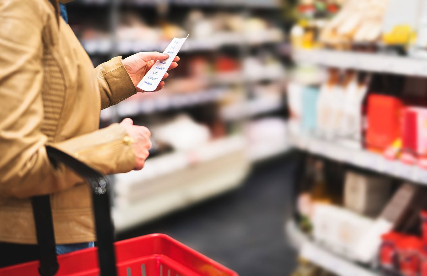 Person in a shop with a basket and shopping list