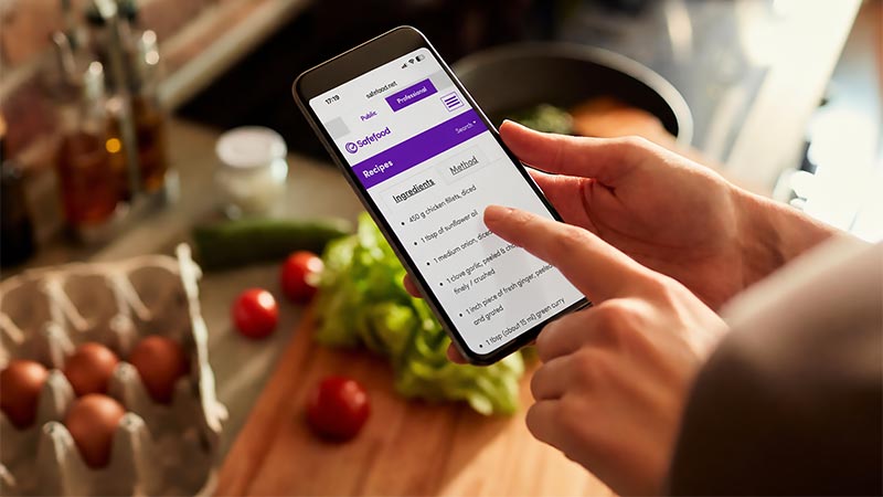 Person using a mobile phone while preparing food in the kitchen