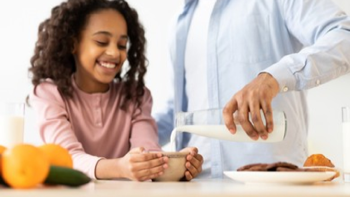 Dad pours a milk drink for his daughter