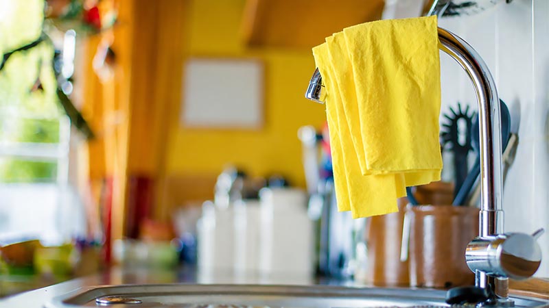 Clean dishcloth hanging by a kitchen sink in normal lighting