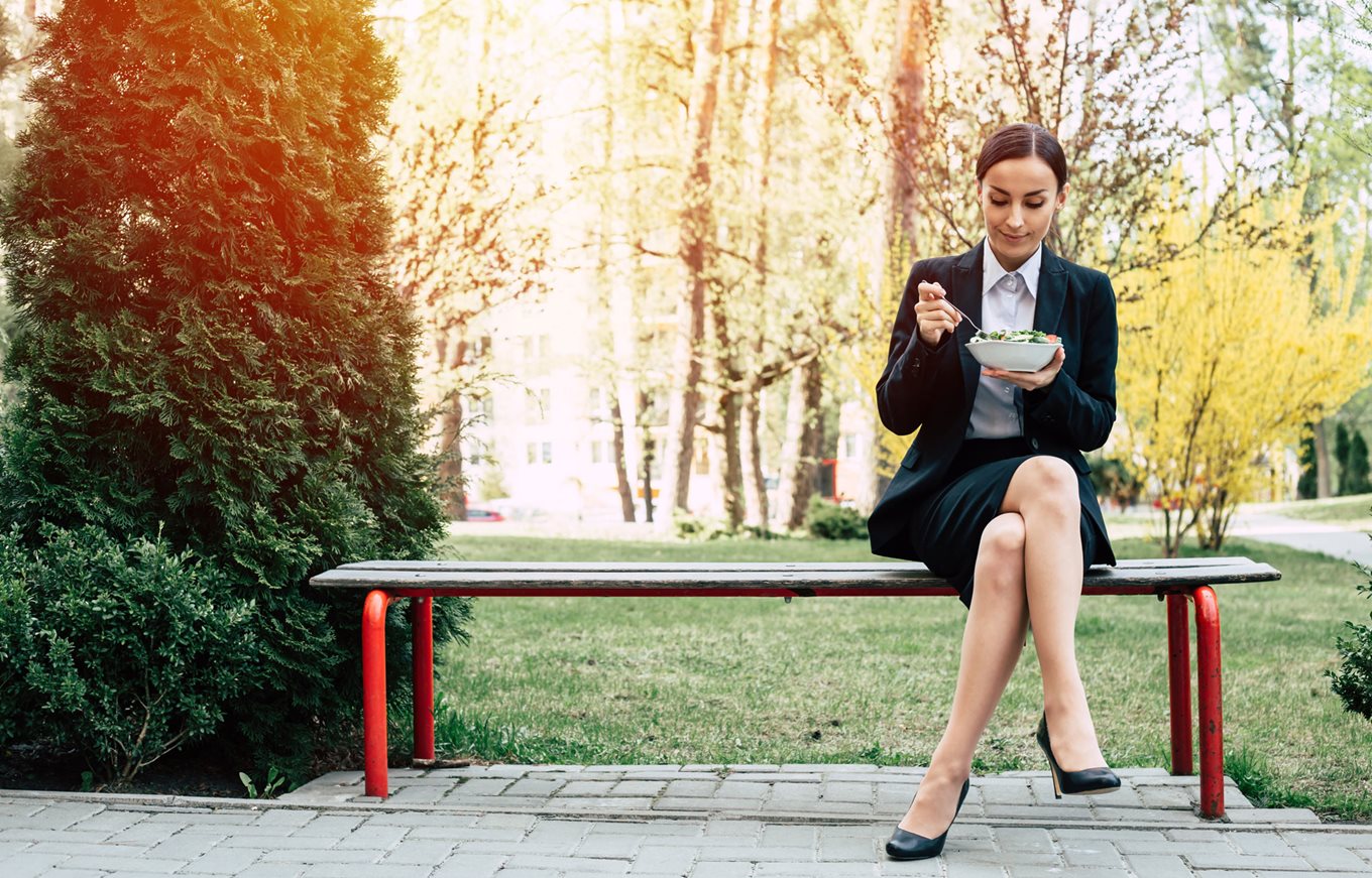Office worker having lunch on a park bench