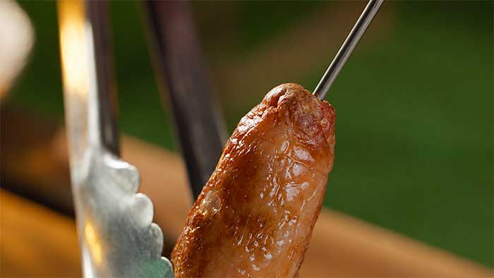 Meat thermometer probe inserted lengthways through a sausage