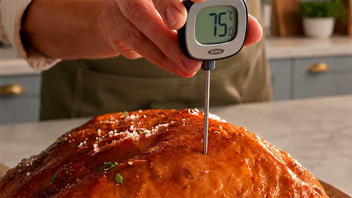 Meat thermometer probe inserted through the thickest part of a turkey crown