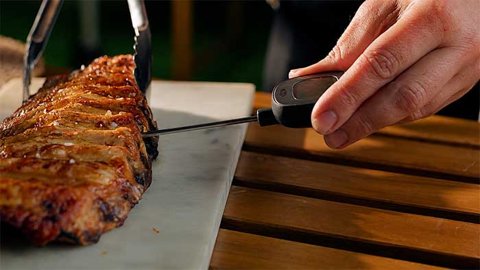 Meat thermometer probe inserted between the bones of spare ribs