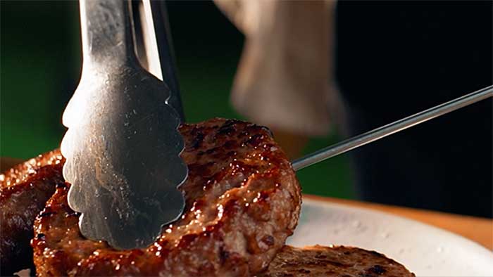 Meat thermometer probe inserted horizontally into burger