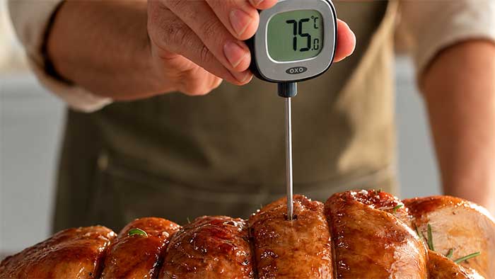 Meat thermometer probe inserted in the centre of a boned and rolled turkey