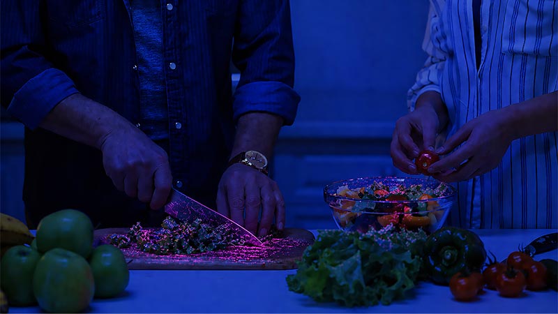 Knife and chopping board under UV light showing bacteria transferring to ready-to-eat food