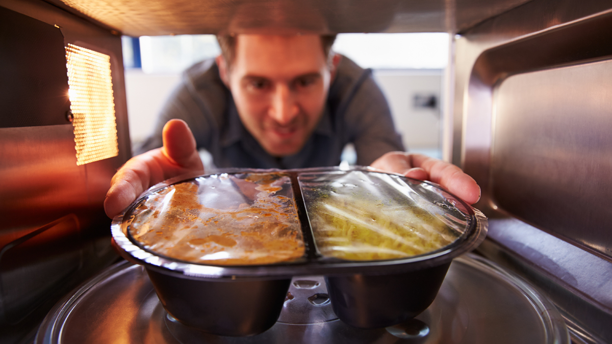 Man taking prepacked curry out of the microwave