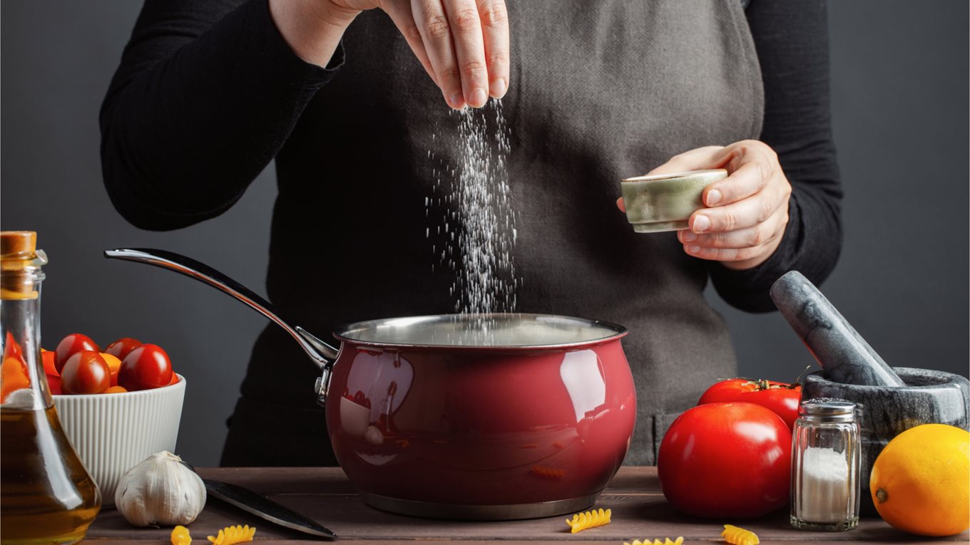 Woman adding salt to a cooking pot