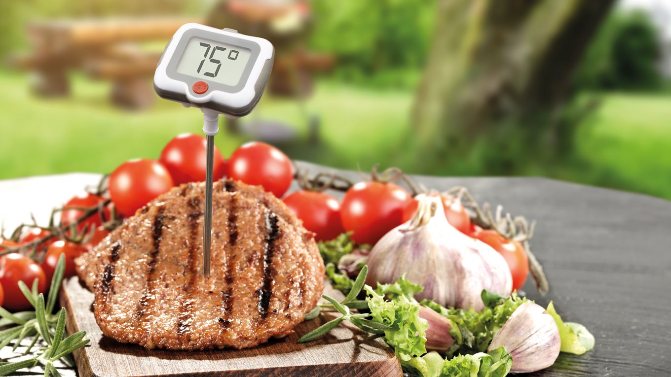 Man testing burgers are cooked with meat thermometer