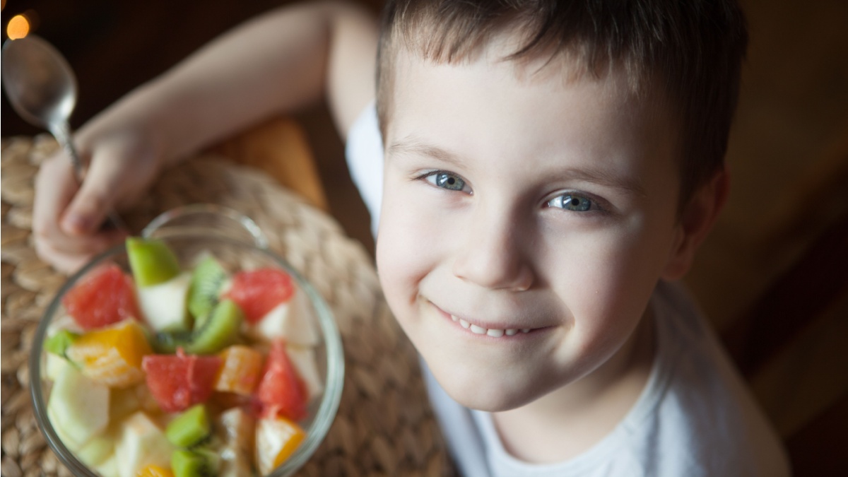 Young boy eating a bowl of fruit salad