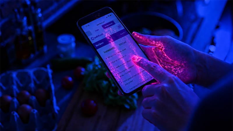 Mobile phone under UV light showing bacteria transferred from hands in swipe and tap patterns